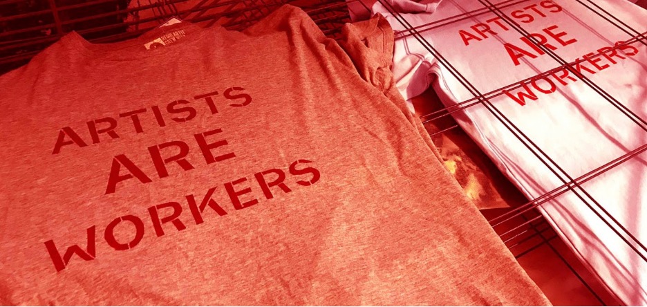 T-shirts with screen printed text Artists are workers. image has red cast.